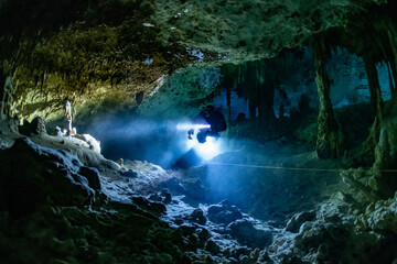 Canvas Print - cave diver instructor leading a group of divers in a mexican cenote underwater