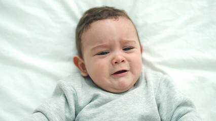 Canvas Print - Adorable hispanic baby lying on bed crying at bedroom