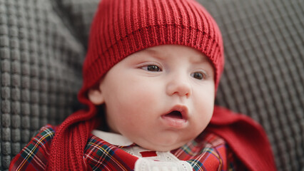 Sticker - Adorable caucasian baby sitting on sofa with relaxed expression at home