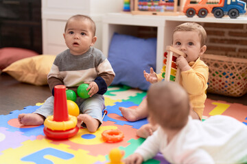 Wall Mural - Group of toddlers playing with toys sitting on floor at kindergarten