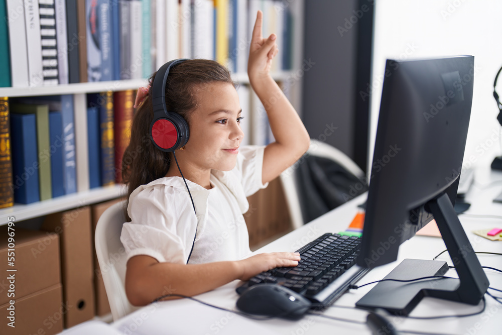 Adorable hispanic girl student using computer and headphones having ...