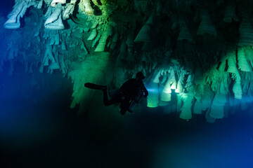 cave diver instructor leading a group of divers in a mexican cenote underwater