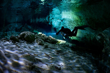 Wall Mural - cave diver instructor leading a group of divers in a mexican cenote underwater