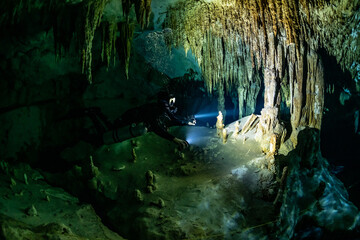 Wall Mural - cave diver instructor leading a group of divers in a mexican cenote underwater