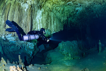 Wall Mural - cave diver instructor leading a group of divers in a mexican cenote underwater