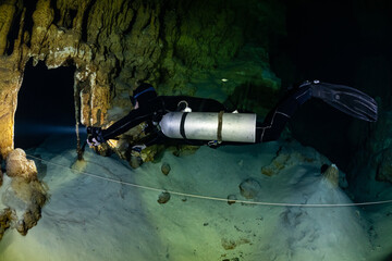 Wall Mural - cave diver instructor leading a group of divers in a mexican cenote underwater