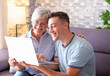 © luciano - Young boy teaching his grandmother how to surf the internet, buy products online while holding the laptop and together watching a video