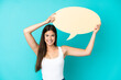 © luismolinero - Young Brazilian woman isolated on blue background holding an empty speech bubble
