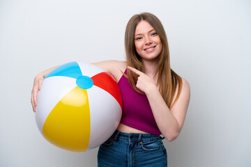 Wall Mural - Young caucasian woman holding beach ball isolated on white background pointing to the side to present a product