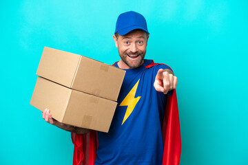 Wall Mural - Super Hero delivery man isolated on blue background surprised and pointing front