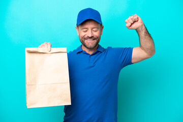 Wall Mural - Middle age man taking a bag of takeaway food isolated on blue background doing strong gesture