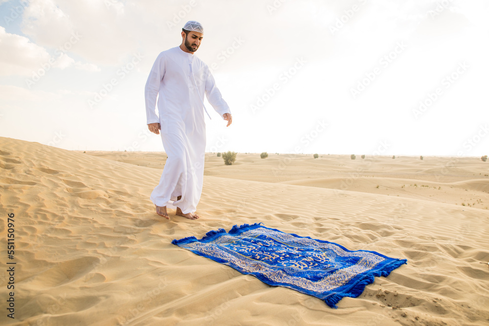 Typical Arab Arab man wearing typical middle eastern clothing in the desert praying ...