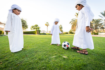 Wall Mural - Cute middle eastern kids wearing traditional arab clothing playing and having fun in a park outdoors