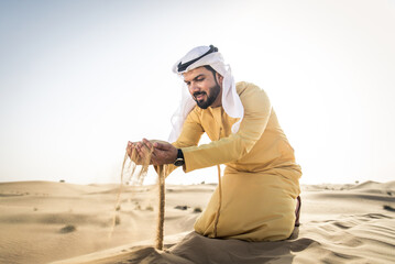 Wall Mural - Handsome arab man wearing traditional middle eastern clothing in the desert