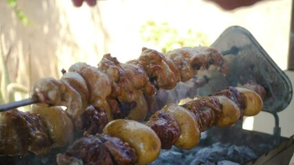 Sticker - Souvla, a popular pork dish from Cyprus cooking on a turning skewer over a charcoal barbecue