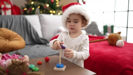 Poster - Adorable caucasian girl playing with toy standing by christmas tree at home