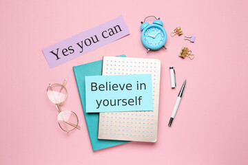 Wall Mural - Notes with motivational quotes, glasses and office stationery on pink background, flat lay