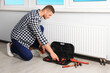 © New Africa - Professional plumber with different tools installing new heating radiator in room