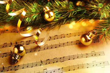 Wall Mural - Fir branches, golden streamer and Christmas balls on music sheets, closeup