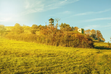 Wall Mural - Watchtower on the green meadow on a sunny day.Autumn landscape.