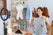 © Pichsakul - Online shopping concept, Young Asian women hold clothes to present and selling on video streaming