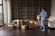 © fizkes - Real estate property buyer man moving into new apartment, carrying cardboard boxes into empty room to heap of containers, enjoying relocation process, doing logistic work. Full length
