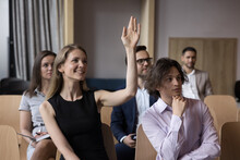 People Take Part In Conference Or Seminar Gather In Office, Attractive Smiling Woman Raising Hand, Asking Question To Business Trainer. Volunteering, Voting Or Educational Workshop Of Corporate Staff