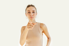 Young Confident Successful Girl Of 20s Pointing Index Finger At Camera, Choosing You To Join Her Team, Motivating To Achieve Your Goals, Isolated On White Studio Background In Beige Tank Top
