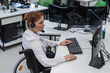 © Михаил Решетников - Red-haired caucasian woman in a wheelchair talking on a headset. Female call center worker at her desk.
