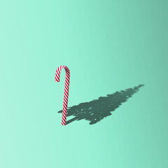 Christmas minimal concept with candy cane and shadow in the shape of a Christmas tree. Creative Christmas or New Year party background with copy space