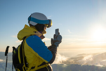 Canvas Print - woman skier taking picture of sunset above the mountains