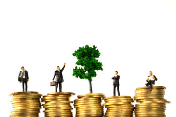 Business Money and Financial Concept. four businessman miniature people figure and green tree standing on top of stack of gold coins on white background with copy sapce.