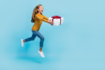 Poster - Full size profile portrait of excited crazy girl hands hold giftbox jumping rush isolated on blue color background