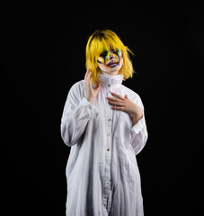 Wall Mural - Woman in white shirt with yellow hair and evil clown face art posing on black background