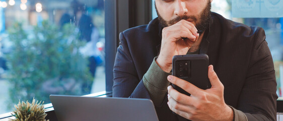 portrait of a successful businessman Working on a laptop computer and using a smartphone to work in a coffee shop.