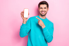 Photo Of Young Toothy Beaming Smile Guy Student Wear Blue Sweater Hold Phone Finger Direct Empty Space Touchscreen Isolated On Pink Color Background