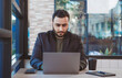 © atitaph - portrait of a successful business man Working on laptop computer and drinking coffee working in coffee shop
