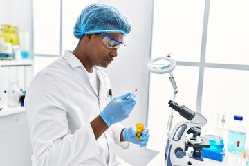 Wall Mural - Young south east man wearing scientist uniform holding pill at laboratory