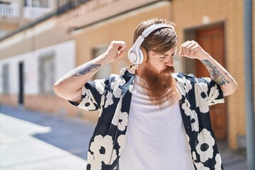 Wall Mural - Young redhead man listening to music and dancing at street