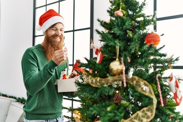 Canvas Print - Young redhead man smiling confident decorating christmas tree at home