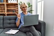 © Krakenimages.com - Young man working using computer laptop sitting on the sofa smiling happy pointing with hand and finger to the side
