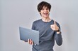 © Krakenimages.com - Young man working using computer laptop smiling happy and positive, thumb up doing excellent and approval sign