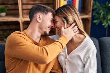 Poster - Young man and woman couple hugging each other sitting on sofa at home