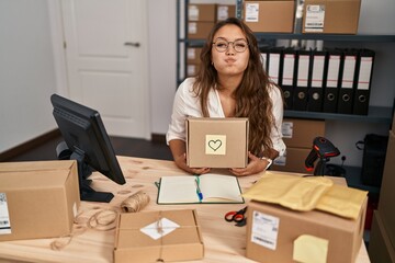 Poster - Young hispanic woman working at small business ecommerce puffing cheeks with funny face. mouth inflated with air, catching air.