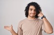 © Krakenimages.com - Hispanic man with curly hair standing over white background confused and annoyed with open palm showing copy space and pointing finger to forehead. think about it.