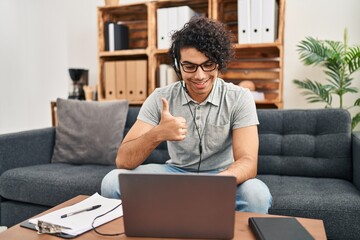 Poster - Hispanic man with curly hair doing online session at consultation office smiling happy and positive, thumb up doing excellent and approval sign