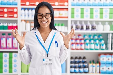 Sticker - Hispanic woman working at pharmacy drugstore crazy and mad shouting and yelling with aggressive expression and arms raised. frustration concept.