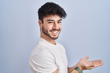 Canvas Print - Hispanic man with beard standing over white background pointing aside with hands open palms showing copy space, presenting advertisement smiling excited happy