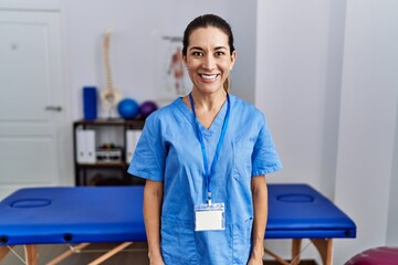 Canvas Print - Young hispanic woman wearing physiotherapist uniform standing at clinic with a happy and cool smile on face. lucky person.