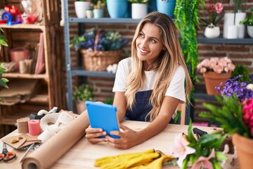 Poster - Young blonde woman florist smiling confident using touchpad at florist